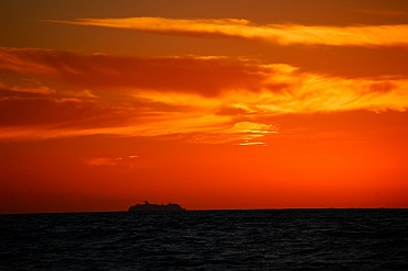 A cruise ship heading north passes us at sunset.