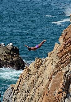 Cliff diver soars off the rocks at La Quebrada.