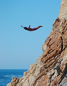Cliff diver soars off the rocks at La Quebrada.